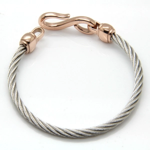 Detail of twisted cable steel bracelet with rose gold S-hook clasp and industrial design