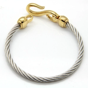 Detail of twisted cable stainless steel bracelet with golden S-hook clasp and texture