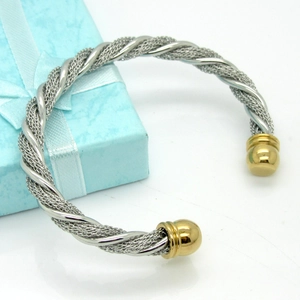 Macro detail of silver twisted cable bracelet featuring gold polished ball end caps