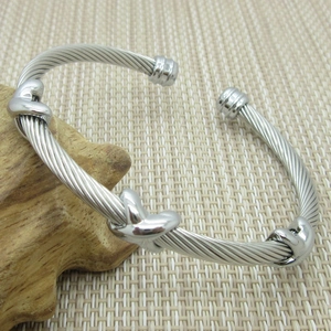 Close-up of silver stainless steel cable bracelet with triple knot detail and ball ends