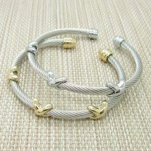 Macro detail of twisted cable bangles featuring X-shaped and heart metal motifs