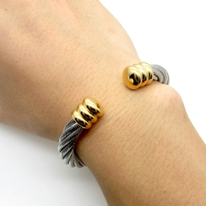 Two-tone stainless steel cable cuff bracelet worn on wrist featuring a minimalist rope design