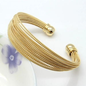 Close-up of golden multi-layer twisted cable open cuff bracelet with spherical ends