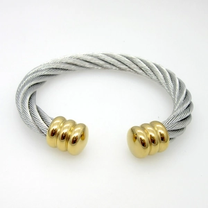 Macro detail of two-tone braided cable cuff bracelet with polished gold screw ends
