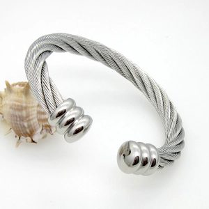 Detail of silver twisted cable cuff bracelet with smooth spherical ends on white background