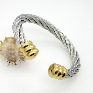 Detail of silver twisted cable bracelet with golden ball ends and engraved ring accents