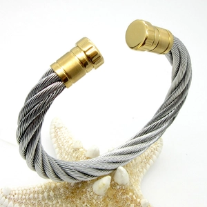 Macro detail of twisted steel cable bracelet with gold-tone polished metal end caps