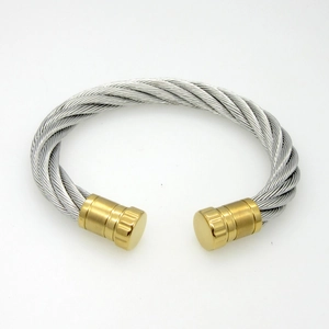 Macro view of cable wire bangle with silver braided steel and matte gold caps