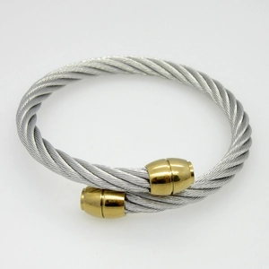 Detailed macro of twisted steel rope cable bracelet with polished gold cylinder end caps