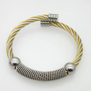 Detail of twisted cable cuff bracelet in gold and silver finish with ball ends