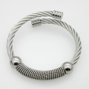 Detail of twisted cable steel open cuff bracelet with polished silver beads and industrial texture