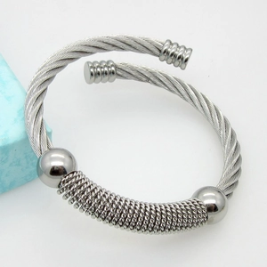Macro detail of silver twisted cable cuff bracelet with polished beads and spring texture