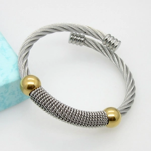 Macro detail of silver twisted wire cable bangle with gold spherical bead accents