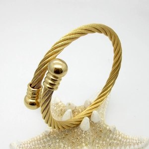 Macro shot of gold-plated titanium steel cable bracelet featuring spiral rope texture