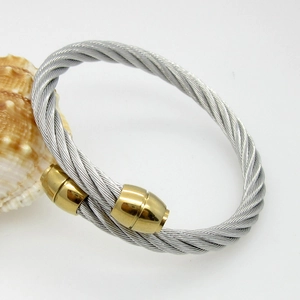 Detailed close-up of twisted steel cable open bangle with golden cylindrical end caps