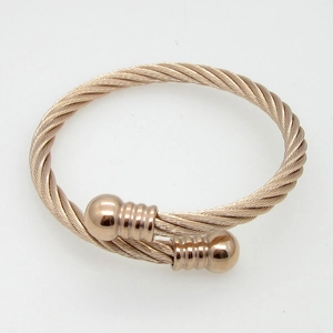 Macro view of rose gold twisted cable cuff bracelet with textured ball end caps