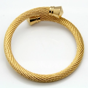 Detail of golden twisted cable bangle with cylinder end caps on white background
