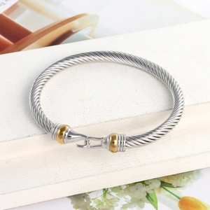 Close-up of two-tone cable twist bangle featuring silver twisted wire and gold hook clasp