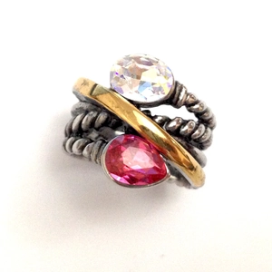 Dettaglio anello a treccia con barra dorata e pietre di cristallo rosa vivace