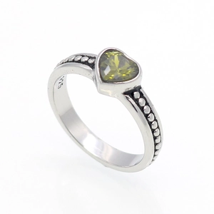 Dettaglio di un anello in argento vintage con zircone verde a cuore e texture a grani