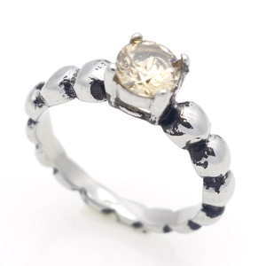 Detail van vintage roestvrijstalen ring met champagne zirkoon en kralenband