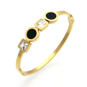 Macro detail of gold-plated hinged bangle with square zircons and black round enamel insets