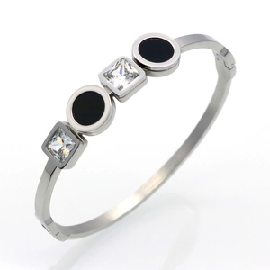 Detail of silver titanium steel bangle featuring black enamel circles and square crystals