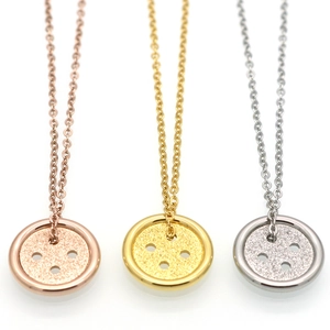 Detail van knoopvormige hangers in roségoud, goud en zilver met een matte glitterafwerking