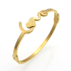 Close-up of gold LOVE bracelet with matte heart detail and side hinge closure