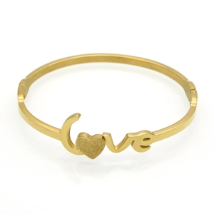 Detailed view of gold love bangle featuring frosted heart and polished finish