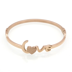 Detail of rose gold Love bangle featuring a frosted heart motif and polished finish