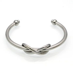Detail of silver stainless steel figure-eight knot bangle with polished ball ends