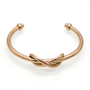 Detailed view of a rose gold knot bracelet with spherical ends and a polished finish