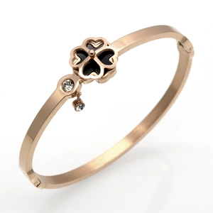 Detail of rose gold clover bracelet with black inlay and sparkling zircon charms