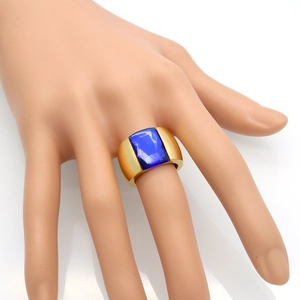 Detail of wide gold-plated titanium ring with large rectangular blue stone on model hand