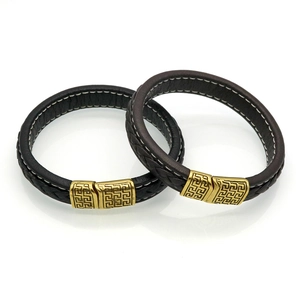 Detail of black and brown leather bracelets with Greek meander pattern on gold buckles