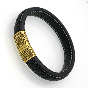 Macro view of black woven leather men's bracelet with gold Greek key pattern metal clasp