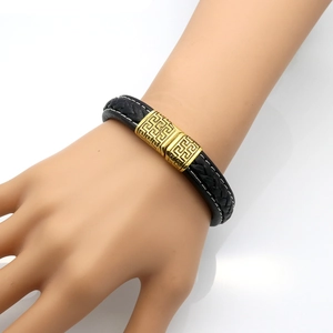 Men's braided leather bracelet with golden Greek key pattern clasp on male wrist