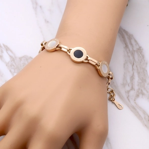 Rose gold Roman numeral bracelet with black and white shell discs on model wrist