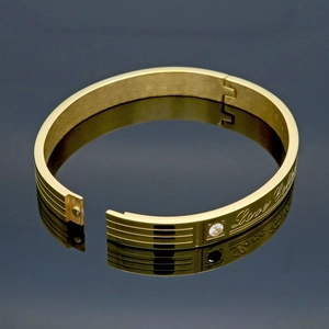 Gold plated stainless steel love engraved bangle with a centered crystal stone inlay