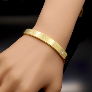 Polished gold titanium steel bangle with Love Collection engraving and cubic zirconia