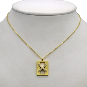 Gold rectangular pendant necklace with X-shaped crystal inlay on a mannequin display