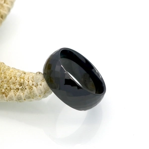 Macro shot of faceted black ceramic ring with geometric surfaces and polished inner band