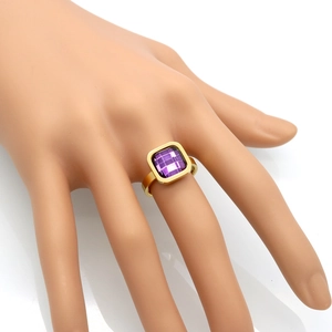 Detail of square-cut purple crystal ring with gold-plated band on finger model