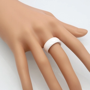 Minimalist white faceted ceramic ring with geometric diamond-cut design on model