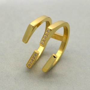 Detail view of double-layered gold ring with sparkling cubic zirconia on textured sand