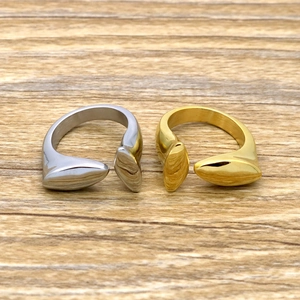 Close-up of T-shaped open rings in polished gold and silver finishes on wood