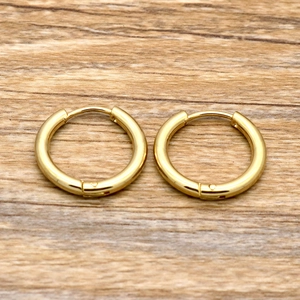 Close-up of polished gold hoop earrings presented on a natural wood surface