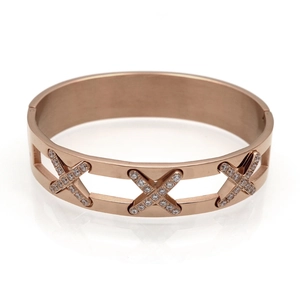 Detailaufnahme eines rosévergoldeten Armreifs mit X-Motiv und glitzernden Kristalldetails