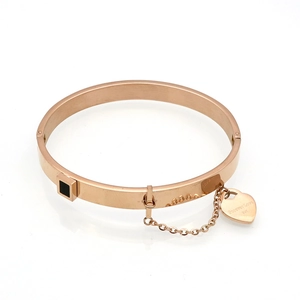 Detail of rose gold bangle with black inlay and heart charm engraved with Forever Love